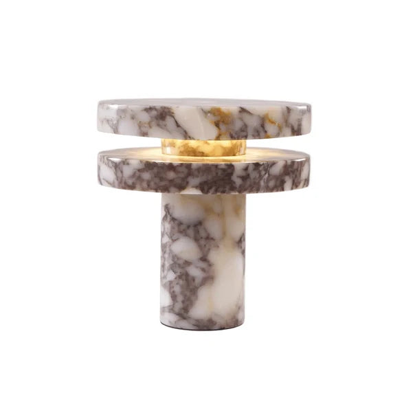 A modern table lamp made of stacked circular marble plates and a matching marble column base, with a warm yellow-gold inner ring visible between the upper tiers, set against a plain white background.